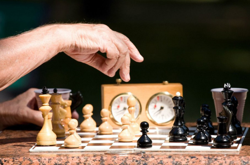 Шахматы: взрослый мужчина играет в шахматы, увлеченный игрой.